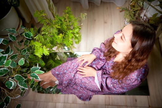 The woman relaxes among vibrant plants, showcasing a harmonious blend of indoor decor and natural elements.