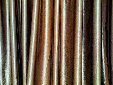 Rich brown silk curtains cascade gently, adding texture and warmth to the ambiance of a stylish room through soft, elegant folds.