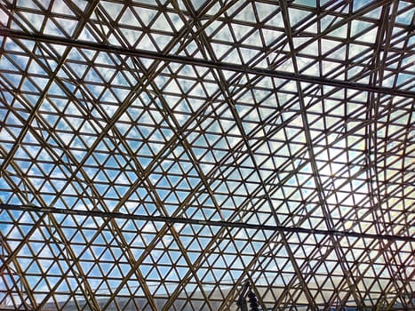 The sunlight filters through a complex array of glass panels forming a geometric pattern, creating an impressive architectural detail.