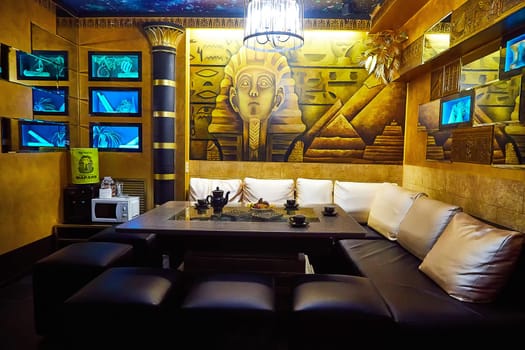 Kirov, Russia - November 10, 2021: Guests relax on cozy seating surrounded by artistic Egyptian motifs and warm lighting