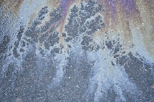 Multicolored oil sheen on the asphalt, creating an attractive abstract pattern.