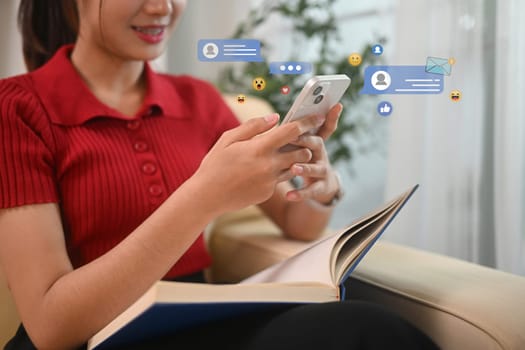 Young woman using smartphone with virtual social media and messaging icons floating around.