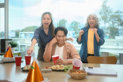 Cheerful group of colleagues enjoying snacks and drinks during a lively office party.
