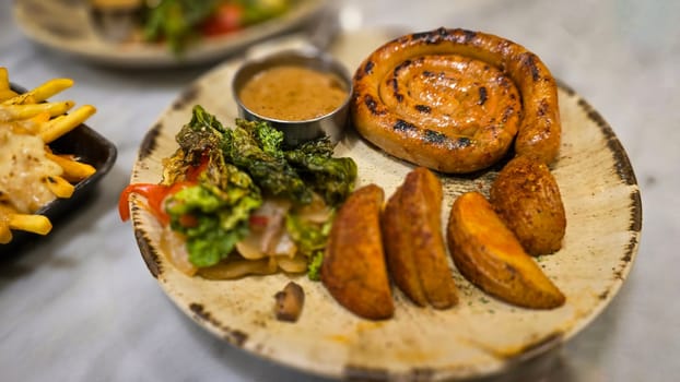 mouthwatering German worst curled up cumberland sausage meal featuring a grilled sausage, loaded cheese fries, and fresh vegetables served on a rustic plate. Perfect for dinner lovers appreciating hearty and flavorful dishes.