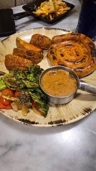mouthwatering German worst curled up cumberland sausage meal featuring a grilled sausage, loaded cheese fries, and fresh vegetables served on a rustic plate. Perfect for dinner lovers appreciating hearty and flavorful dishes.