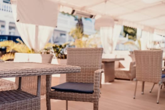 Wicker furniture tables in the open air are waiting for visitors. The interior of the restaurant in the open air. Empty tables of street cafe