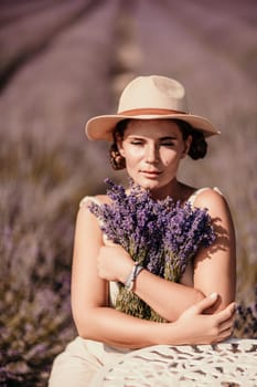 A woman is sitting in a field of lavender flowers and wearing a straw hat. She is smiling and holding a bouquet of flowers. Scene is peaceful and serene, as the woman is surrounded by the beauty of nature.