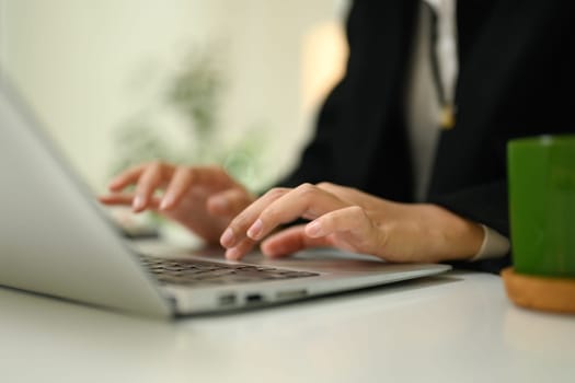 Close up businesswoman hands typing on a laptop chatting, answering or searching information.