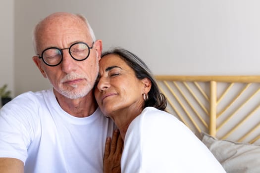 Mature couple relaxing together at home. Eyes closed. Feeling connection and love. Heterosexual couple concept.