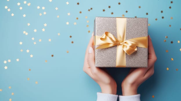 A woman hands hold an elegant gift box with a golden ribbon surrounded by colorful confetti. Perfect for celebrations, holidays, and gifting occasions like Christmas or Valentines Day