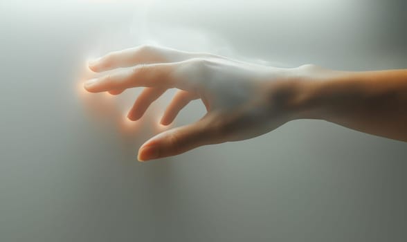 A human hand glowing from within on a light background. Selective focus.