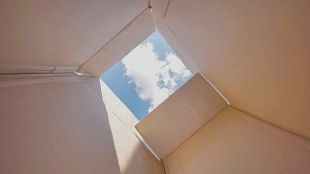 Open cardboard box is revealing a blue sky with some clouds, suggesting freedom, hope and new possibilities.