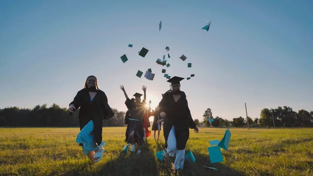 College graduates run into the sunset and throw books and notebooks up in the air