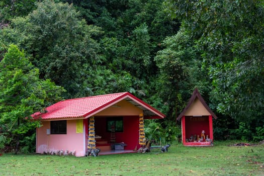 Two colorful cottages are beautifully nestled within a vibrant green landscape, encircled by tall trees