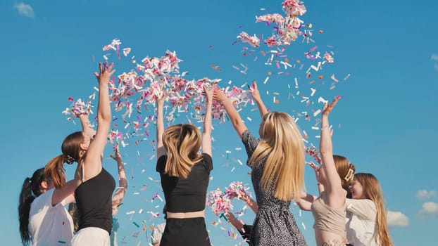 Group of friends throwing confetti in the air while partying outdoors