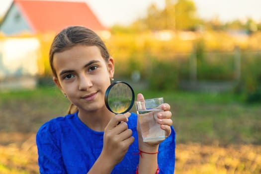 A child looks at water through a magnifying glass. Selective focus. kid.