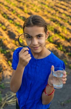 A child looks at water through a magnifying glass. Selective focus. kid.