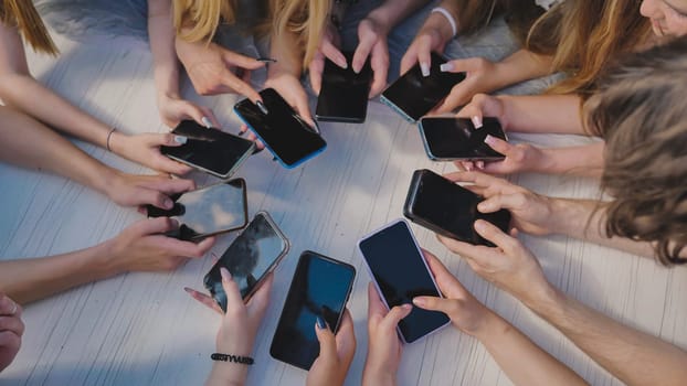 People holding their smartphones around a white table, using their devices and showing a sense of community