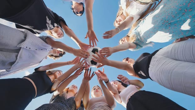 Friends join hands over a soccer ball and then toss it above them