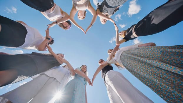 Group of women forming heart shape with their hands up in the air