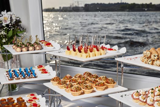 A beautifully arranged buffet that features a wide variety of delicious appetizers alongside a scenic water view