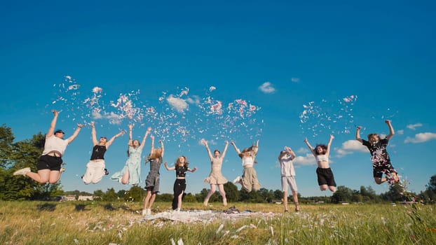 Friends toss colorful paper confetti from their hands against the rays of the evening sun.