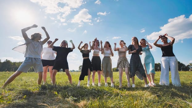 School friends dancing in a meadow on a summer afternoon