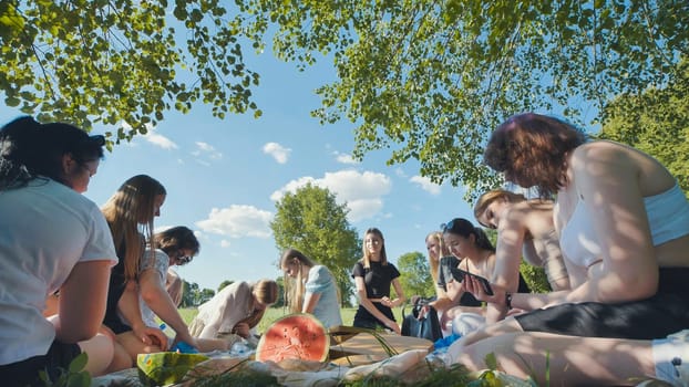 The joyous ambiance of a garden party, with a diverse group of people relishing a shared meal amidst nature's beauty.