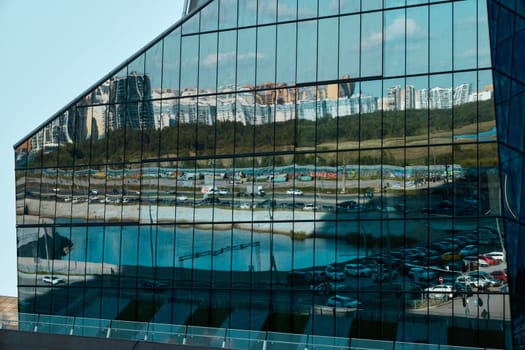A striking reflection of a vibrant cityscape appears on a sleek glass building showcasing modern architecture