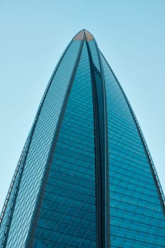 A breathtaking view of a contemporary skyscraper showcasing a sleek glass design that shines under a clear blue sky