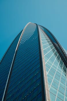 A breathtaking view of a sleek skyscrapers reflective glass facade soaring high into the clear blue sky