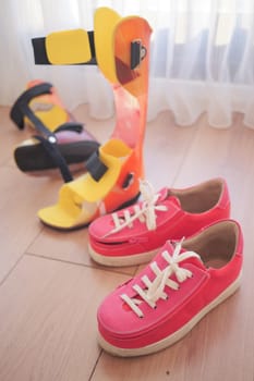 Colorful Orthopedic Braces and Pink Sneakers on Wooden Floor