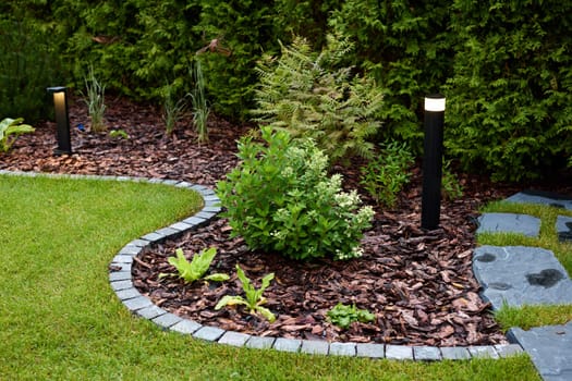 A charming garden scene that beautifully showcases lush greenery, decorative stones, and modern lighting designs