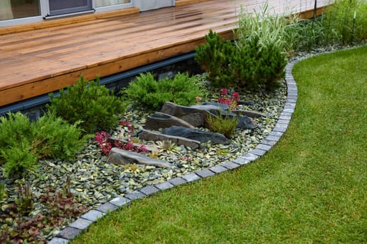 A beautifully arranged garden with elegant stones, vibrant plants, and a manicured lawn creating a serene retreat