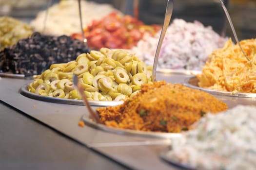 A colorful assortment of olives, fresh salads, and aromatic spices on display for all