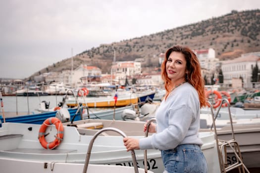 A woman stands in front of a row of boats, some of which have orange life preservers on them. The scene is peaceful and serene, with the boats and the woman creating a sense of calmness and relaxation