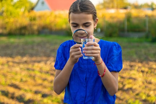 A child looks at water through a magnifying glass. Selective focus. kid.