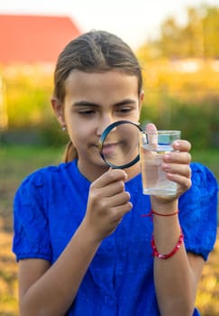 A child looks at water through a magnifying glass. Selective focus. kid.