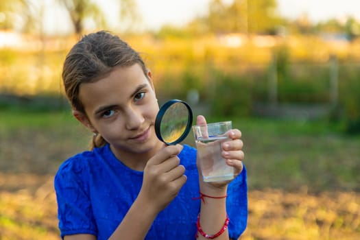 A child looks at water through a magnifying glass. Selective focus. kid.