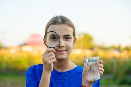 A child looks at water through a magnifying glass. Selective focus. kid.