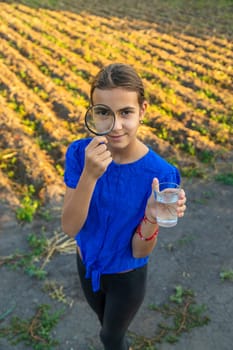 A child looks at water through a magnifying glass. Selective focus. kid.