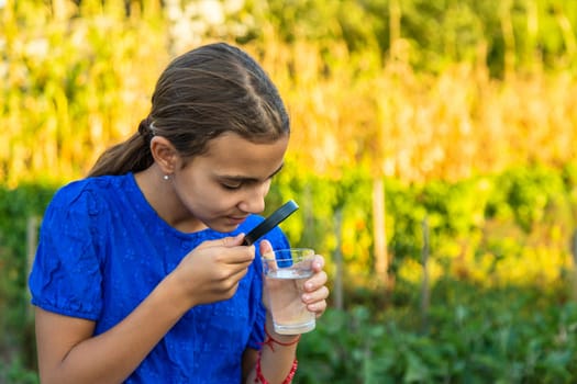 A child looks at water through a magnifying glass. Selective focus. kid.