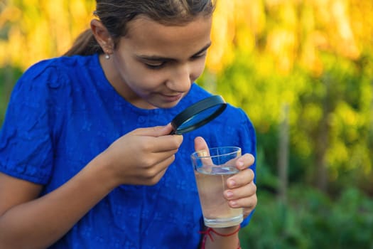 A child looks at water through a magnifying glass. Selective focus. kid.