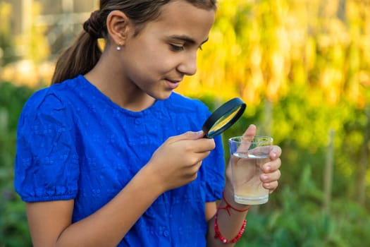 A child looks at water through a magnifying glass. Selective focus. kid.
