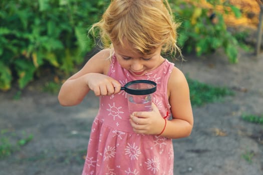 A child looks at water through a magnifying glass. Selective focus. kid.