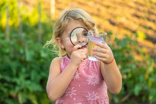 A child looks at water through a magnifying glass. Selective focus. kid.