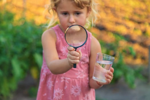 A child looks at water through a magnifying glass. Selective focus. kid.