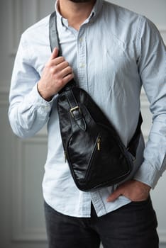 A man in a shirt with holding a black bag on his shoulder