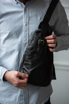 A man in a shirt with holding a black bag on his shoulder