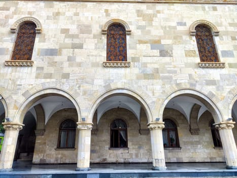 Detailed view of a historic building showcasing ornate arched windows and intricate stonework on a bright day in an urban setting.